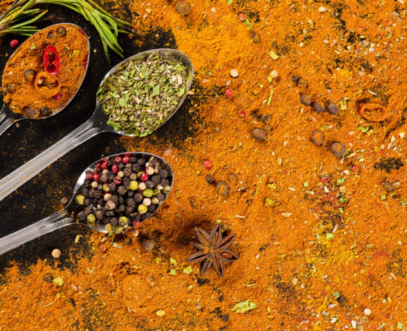 Herbs and spices selection in metal spoons and black background - cooking, healthy eating